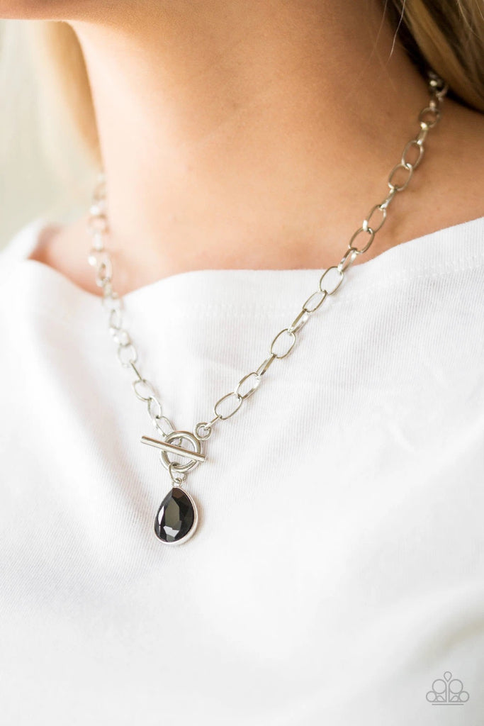 A faceted black teardrop gem swings from the bottom of a shimmery silver chain, creating a classic pendant below the collar. Features a toggle closure.  Sold as one individual necklace. Includes one pair of matching earrings.