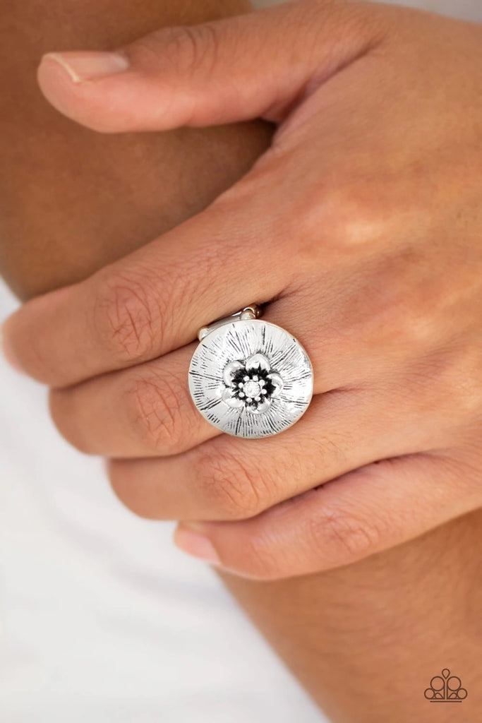 Dotted with a sparkling white rhinestone, a dainty silver flower blooms atop a rounded frame radiating with shimmery silver texture for a seasonal look. Features a stretchy band for a flexible fit.  Sold as one individual ring.