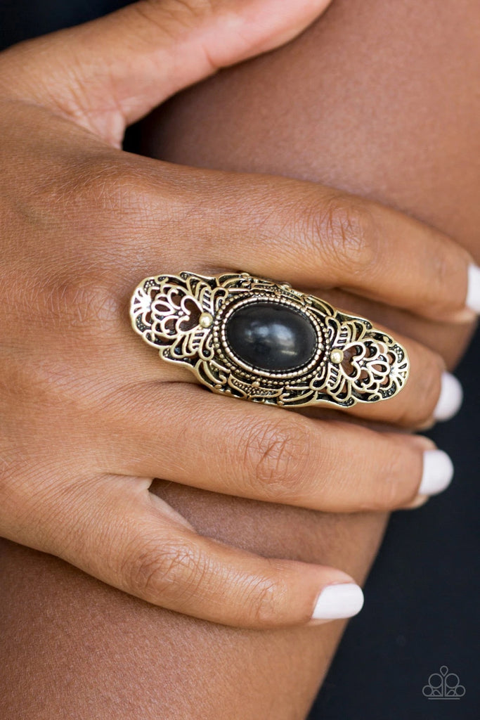 Dotted with an earthy black stone center, glistening brass filigree climbs the finger, coalescing into a dramatic frame. Features a stretchy band for a flexible fit.  Sold as one individual ring.