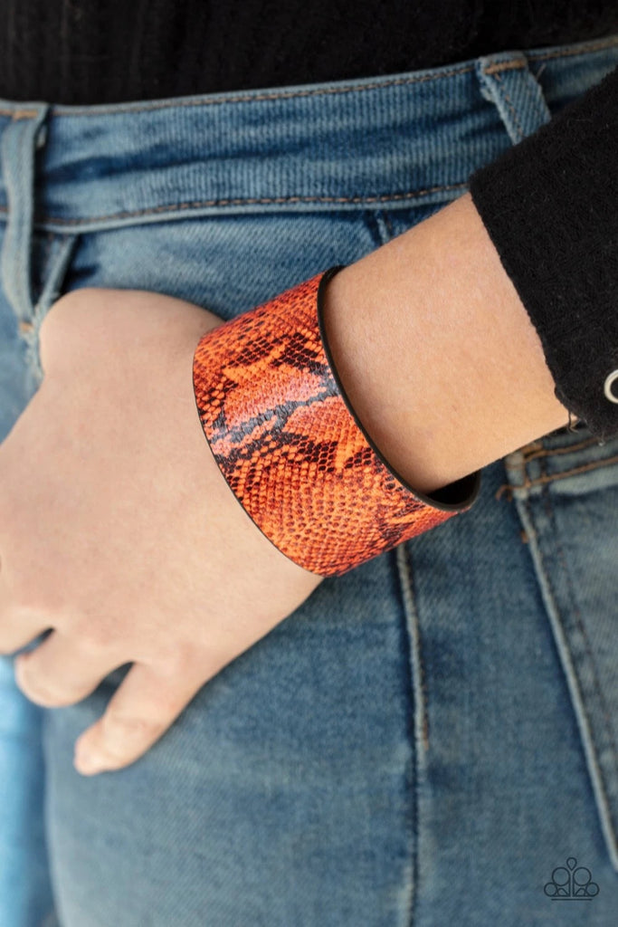 Featuring neon orange python print, a thick leather band wraps around the wrist for a colorfully wild look. Features an adjustable snap closure.  Sold as one individual bracelet.