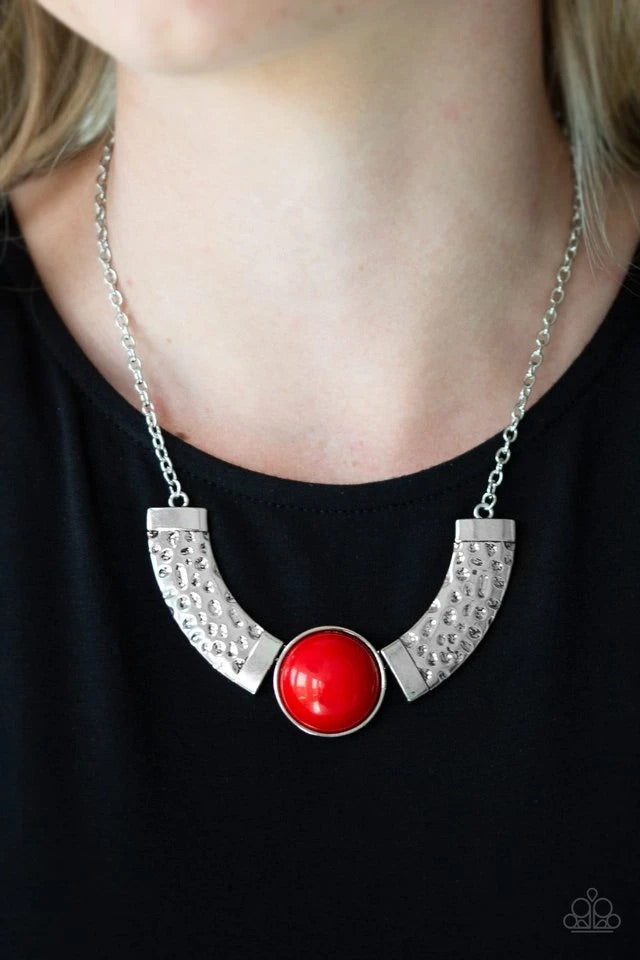 Dramatic silver plates connect with a shiny red beaded center, creating an indigenous collar-like pendant. The shiny silver plates are delicately hammered, adding a flashy metallic texture to the tribal inspired palette. Features an adjustable clasp closure.  Sold as one individual necklace. Includes one pair of matching earrings.