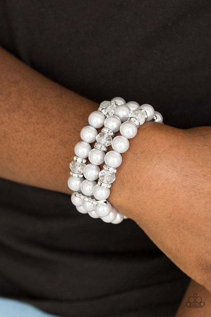 Pinched between white rhinestone encrusted frames, white rhinestone encrusted rings, crystal-beads, and silver pearls are threaded along elastic stretchy bands for a glamorous look.  Sold as one individual bracelet.