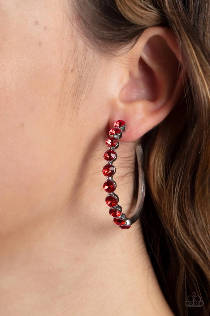 The front of a bold silver hoop is encrusted in fiery red rhinestones, creating a glamorous pop of sparkle. Earring attaches to a standard post fitting. Hoop measures approximately 1 3/4" in diameter.  Sold as one pair of hoop earrings.