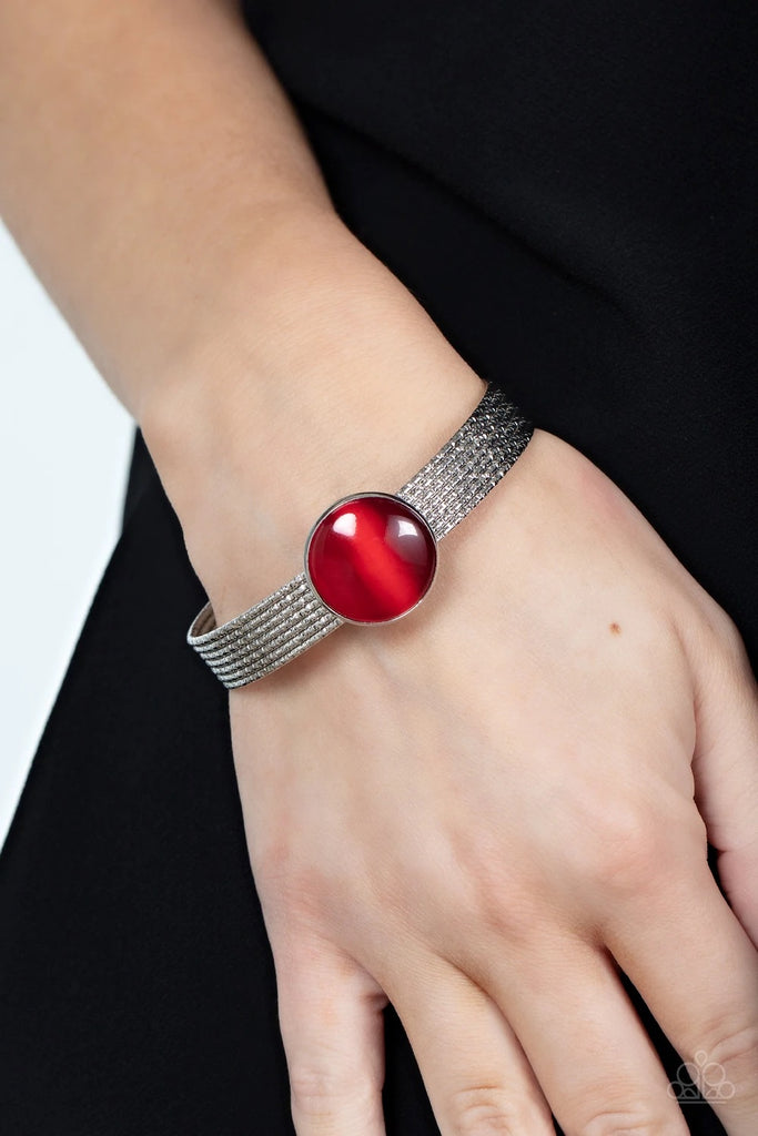 A glassy red cat's eye stone frame sits atop a layered silver cuff that is etched in shimmery textures, creating a glittery centerpiece.  Sold as one individual bracelet.