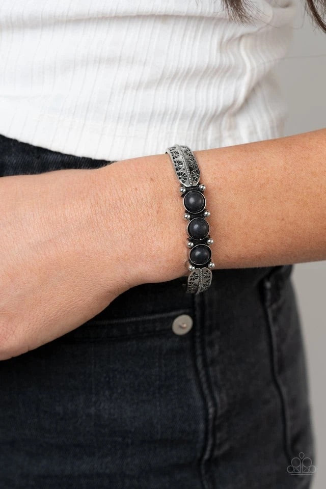 A trio of earthy black stones are encrusted along the center of a dainty silver studded cuff stamped in tribal inspired details for a seasonal flair.  Sold as one individual bracelet.