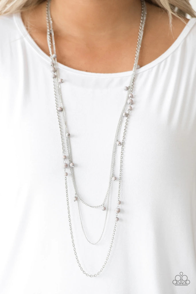 Infused with a plain silver chain, mismatched gray stone beads sporadically trickle along shimmery silver chains, creating earthy layers down the chest. Features an adjustable clasp closure.  Sold as one individual necklace. Includes one pair of matching earrings.