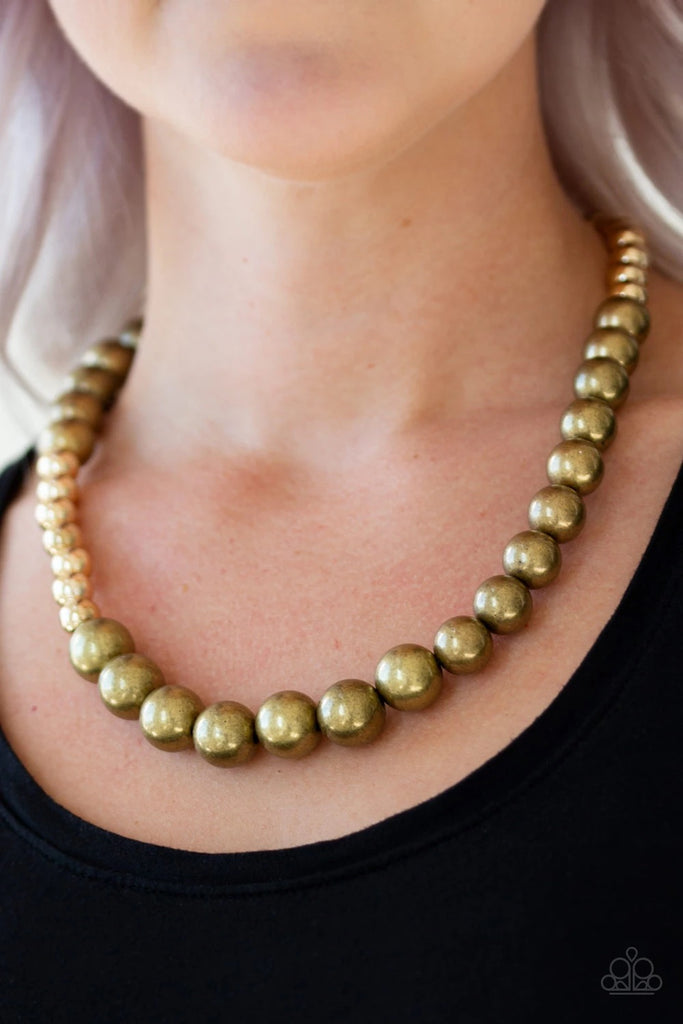 Varying in size, glistening gold and antiqued brass beads drape below the collar in a dramatically asymmetrical fashion. Features an adjustable clasp closure.  Sold as one individual necklace. Includes one pair of matching earrings.  