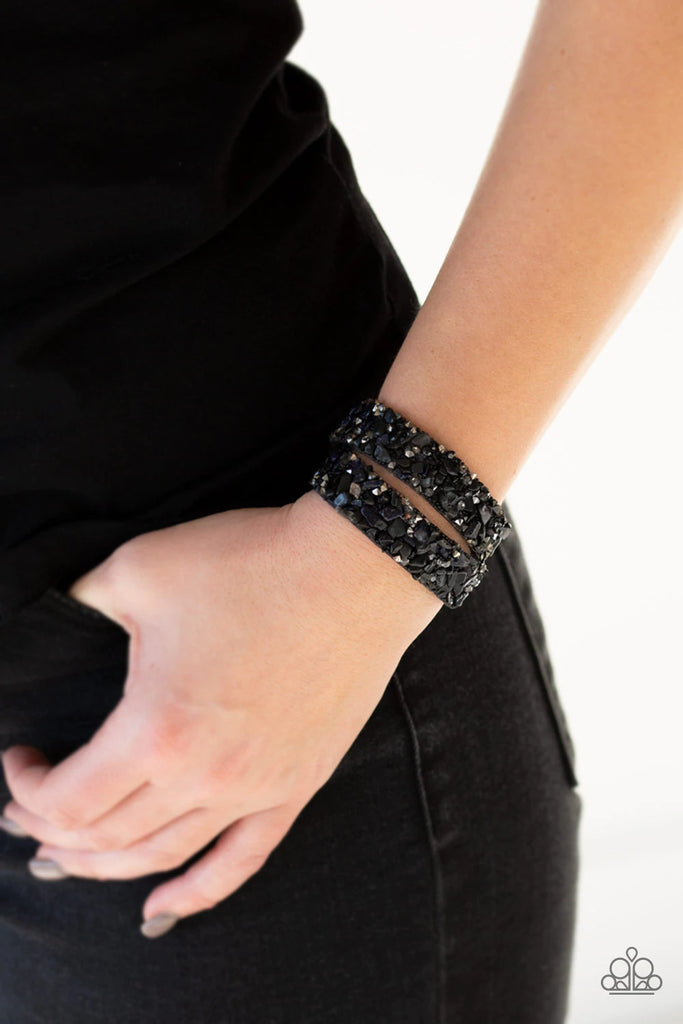 A collection of crushed rocks, smoky and hematite rhinestone prisms are sprinkled across a blue suede band for a seasonal look. The elongated band allows for a trendy double wrap design. Features an adjustable snap closure.  Sold as one individual bracelet.
