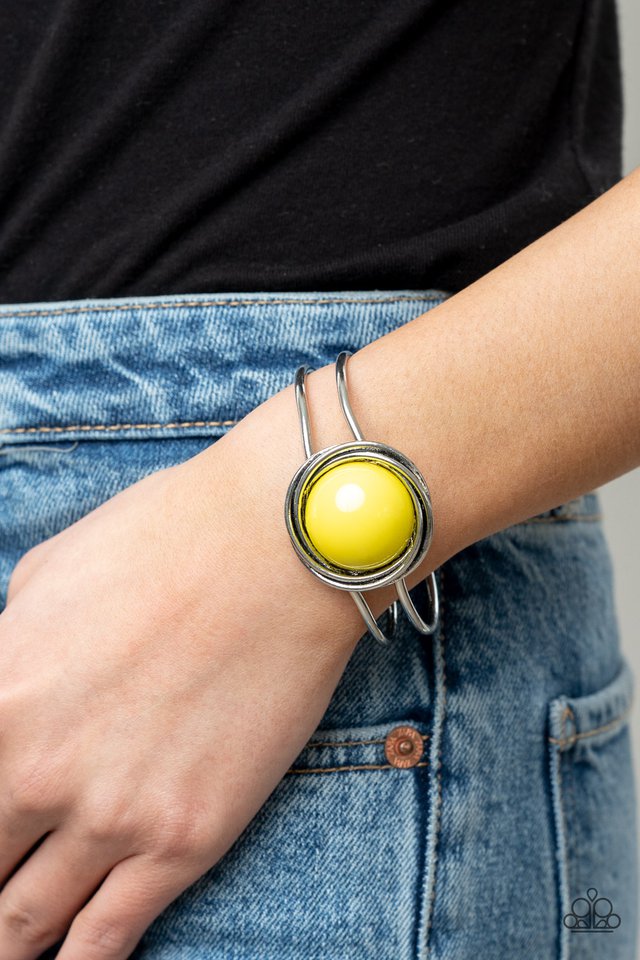 An oversized Illuminating bead is pressed into the center of overlapping silver rings that coalesce into a dizzying centerpiece atop an airy silver bangle-like cuff, creating a bold pop of color atop the wrist. Features a hinged closure.  Sold as one individual bracelet.