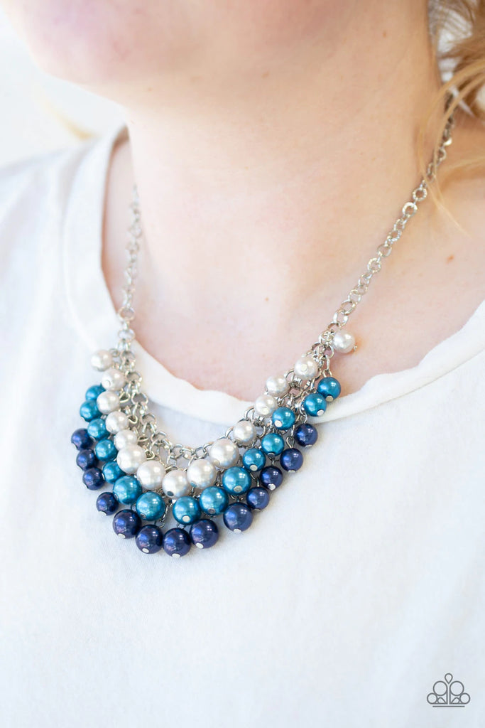 Rows of white, light blue, and dark blue pearls cascade below the collar, creating a glamorous fringe. Features an adjustable clasp closure.  Sold as one individual necklace. Includes one pair of matching earrings.