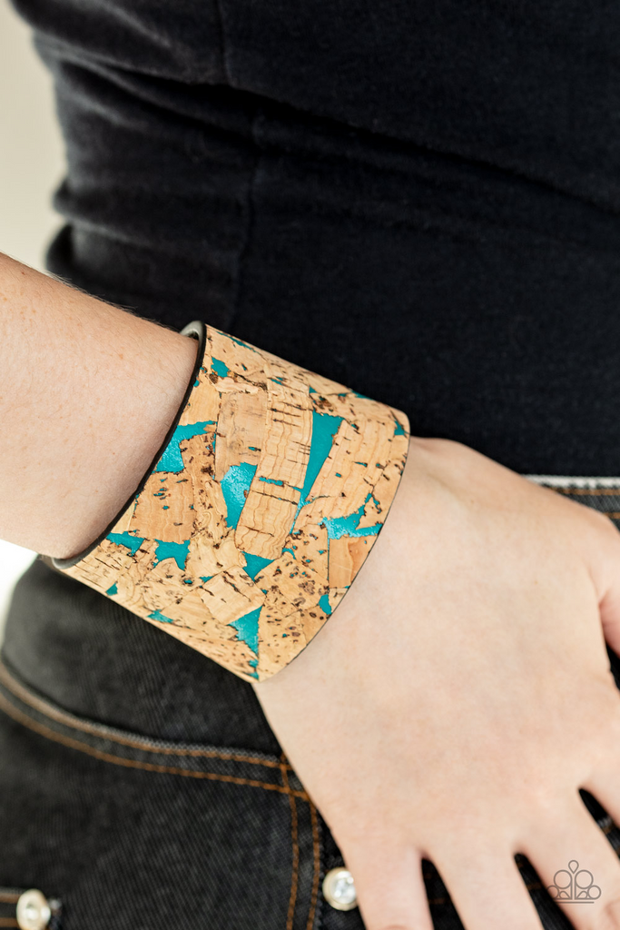 Pieces of cork have been plastered across the front of a blue leather band, creating an earthy look around the wrist. Features an adjustable snap closure.  Sold as one individual bracelet.
