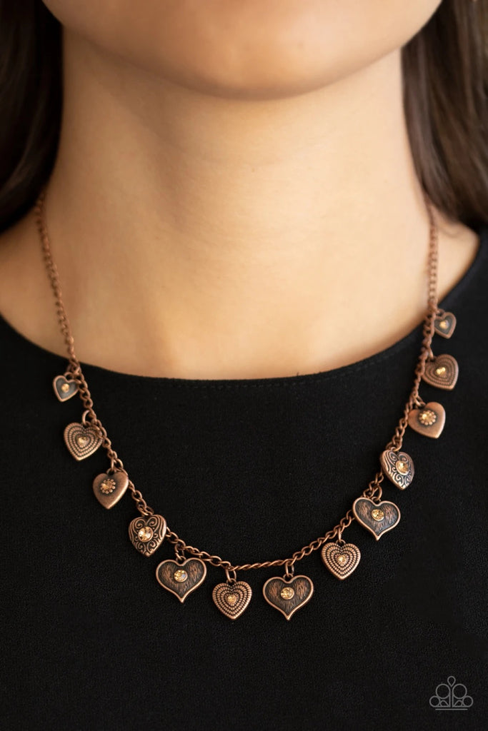 Dotted with glittery topaz rhinestone centers, a mismatched collection of copper heart frames swing from a dainty copper chain below the collar, creating a flirtatious fringe. Features an adjustable clasp closure.  Sold as one individual necklace. Includes one pair of matching earrings.