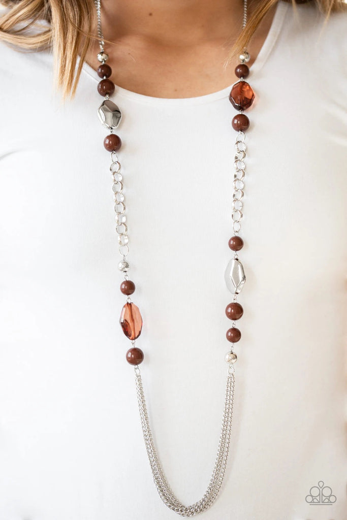 A collection of faceted silver, crystal-like brown, polished brown, and silver beads give way to layers of shimmery silver chains for a whimsical look. Features an adjustable clasp closure.  Sold as one individual necklace. Includes one pair of matching earrings.