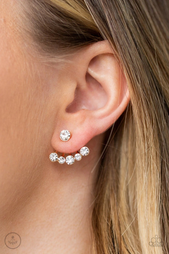 A solitaire white rhinestone attaches to a double-sided post, designed to fasten behind the ear. Radiating with a flared row of glassy white rhinestones, the double sided-post peeks out beneath the ear for an edgy look. Earring attaches to a standard post fitting.  Sold as one pair of post earrings.  
