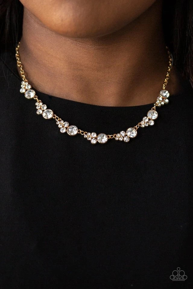 A collection of glassy white rhinestones coalesce into glittery golden frames as they link below the collar for a timeless shimmer. Features an adjustable clasp.  Sold as one individual necklace. Includes one pair of matching earrings.