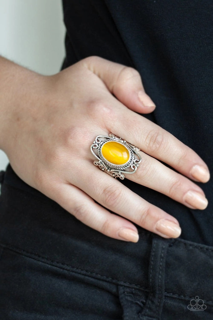 A glowing yellow cat's eye stone is nestled inside of an airy silver frame radiating with frilly filigree for a whimsical look atop the finger. Features a stretchy band for a flexible fit.  Sold as one individual ring.