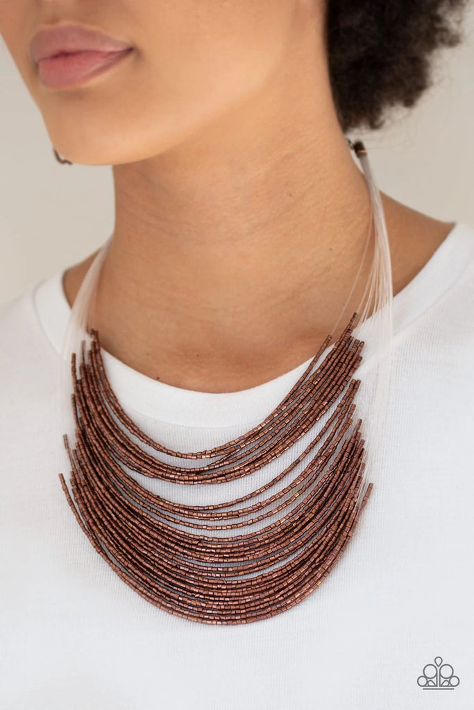 Strand after strand of metallic copper seed beads fall together to create a bold statement piece. Features an adjustable clasp closure.  Sold as one individual necklace. Includes one pair of matching earrings.