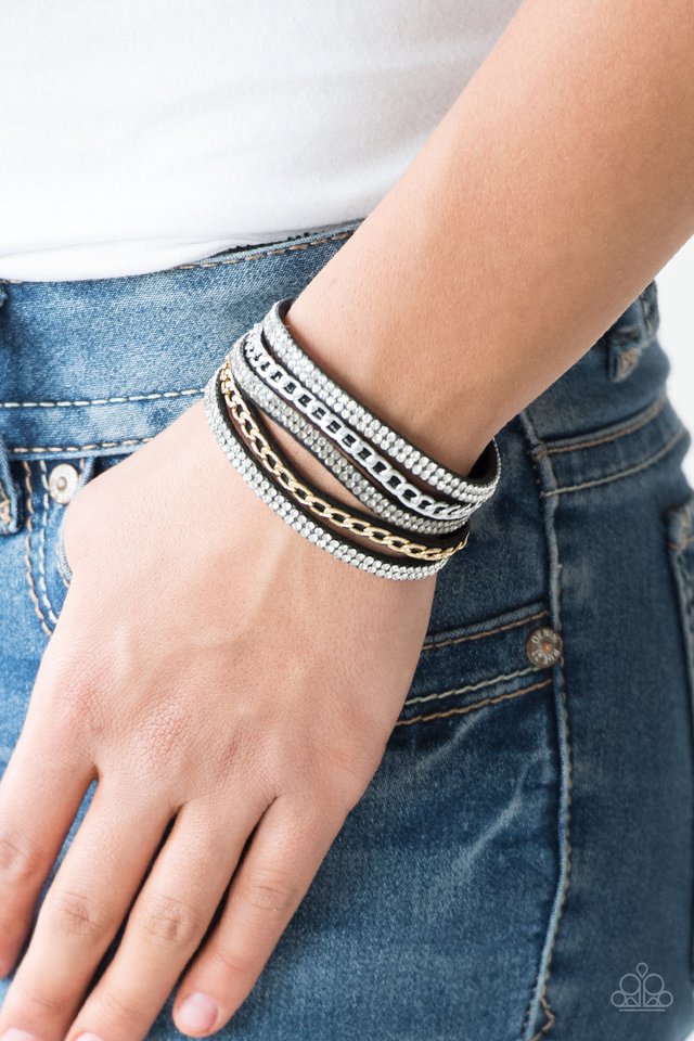 Glassy white and smoky rhinestones are encrusted along strands of black suede. Glistening silver and gold chains are added to the bands, adding edgy industrial shimmer to the sassy palette. Features an adjustable snap closure. Sold as one individual bracelet.
