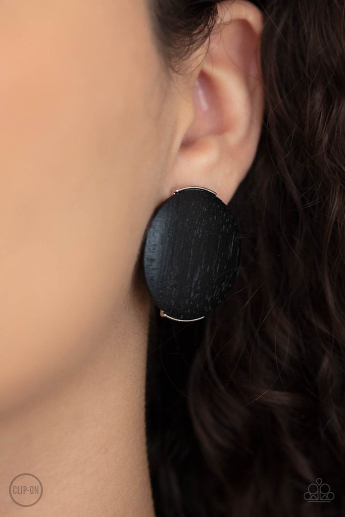 An oversized black wooden disc is fitting in place between a silver frame, creating an earthy effect. Earring attaches to a standard clip-on fitting.  Sold as one pair of clip-on earrings.