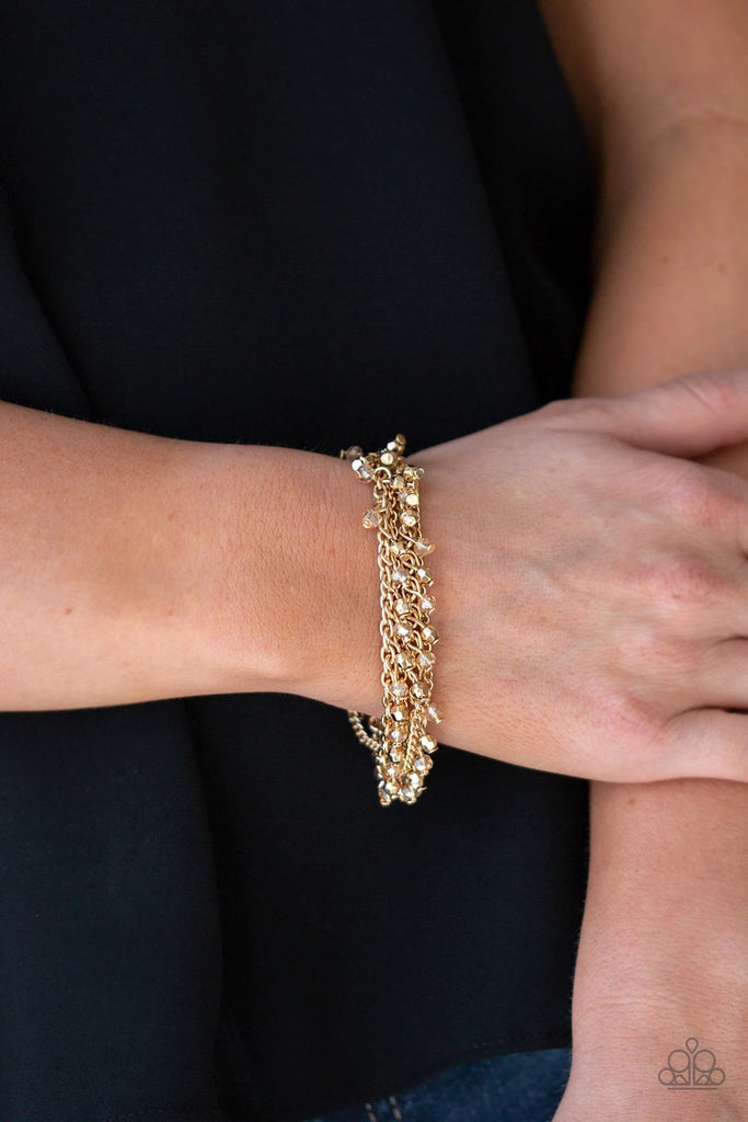 Dainty gold and crystal-like beads cascade from two shimmery gold chains. Infused with plain gold chains, the colorful strands layer around the wrist for a flirtatious look. Features an adjustable clasp closure.  Sold as one individual bracelet.