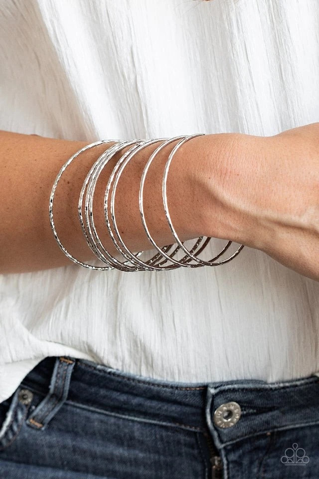 Etched and hammered in shimmery details, a stack of glistening silver bangles stack across the wrist for a flawless finish.  Sold as one set of eight bracelets.
