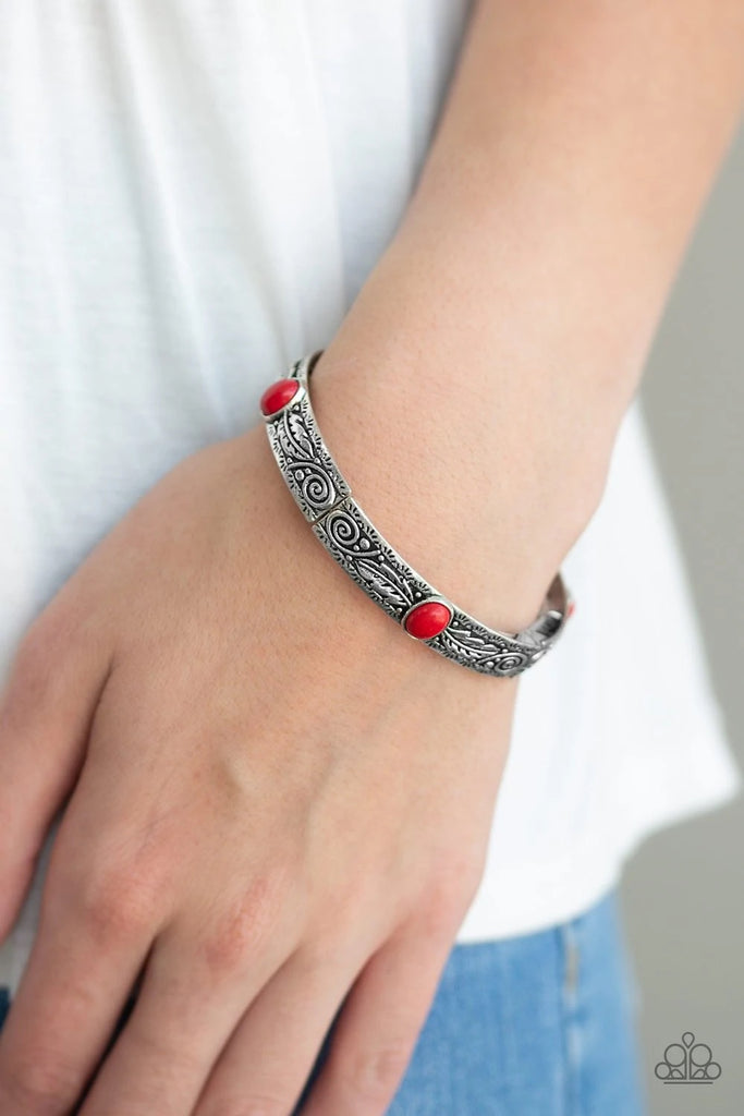 Embossed in swirling silver and feather like detail, antiqued silver frames are threaded along stretchy bands around the wrist. Fiery red stones adorn the centers of the Southwestern frames for a seasonal finish.  Sold as one individual bracelet.