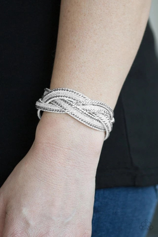 Dusted in glitter, skinny white strands braid with rhinestones encrusted strands across the wrist for a sassy look. Features an adjustable snap closure.  Sold as one individual bracelet.
