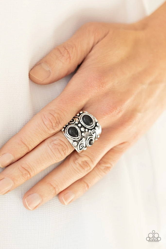 An earthy collection of teardrop and oval black stones are pressed into the front of a thick silver frame studded and embossed in tribal inspired patterns. Features a stretchy band for a flexible fit.  Sold as one individual ring.