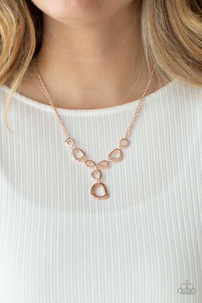 Irregular shaped rose gold rings connect to a rose gold chain as they make their way across the collar. Two rings dangle from the center for a stylish avant-garde fashion. Features an adjustable clasp closure.  Sold as one individual necklace. Includes one pair of matching earrings.