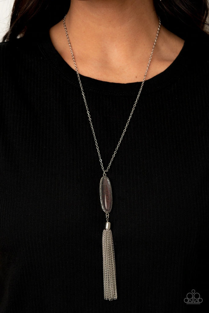 A shimmery silver tassel streams from the bottom of a glittery beaded pendant, creating a dazzling look at the bottom of a lengthened silver chain. Features an adjustable clasp closure.  Sold as one individual necklace. Includes one pair of matching earrings.  