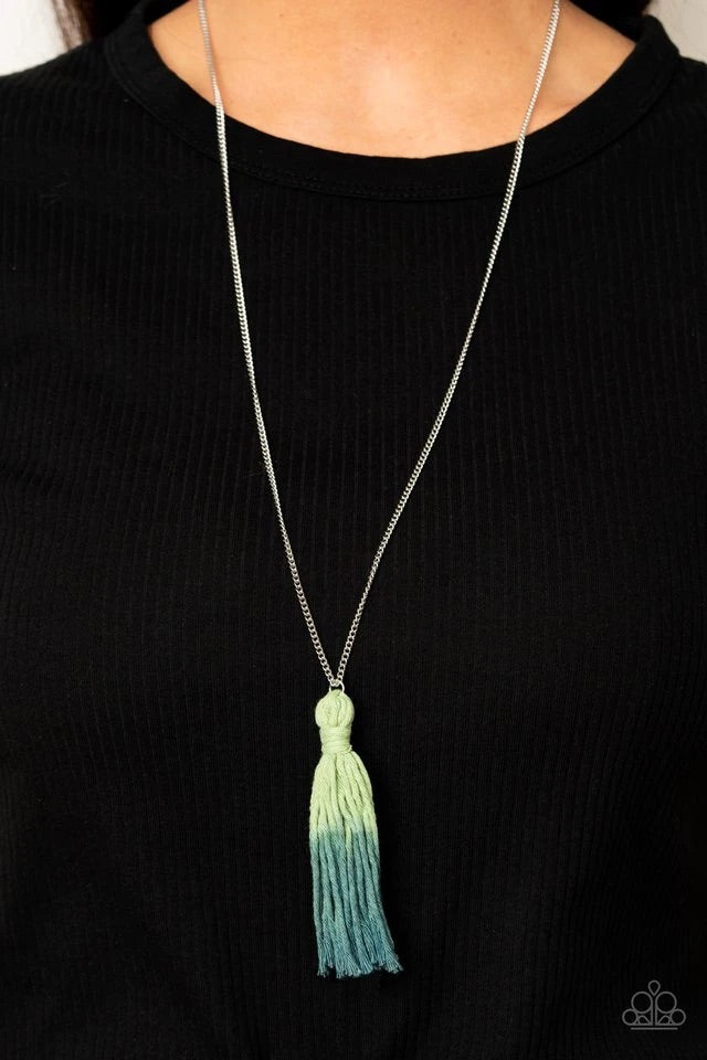 A knotted tassel gradually fades from green to blue at the bottom of a lengthened silver chain, creating a colorful pendant. Features an adjustable clasp closure.  Sold as one individual necklace. Includes one pair of matching earrings.