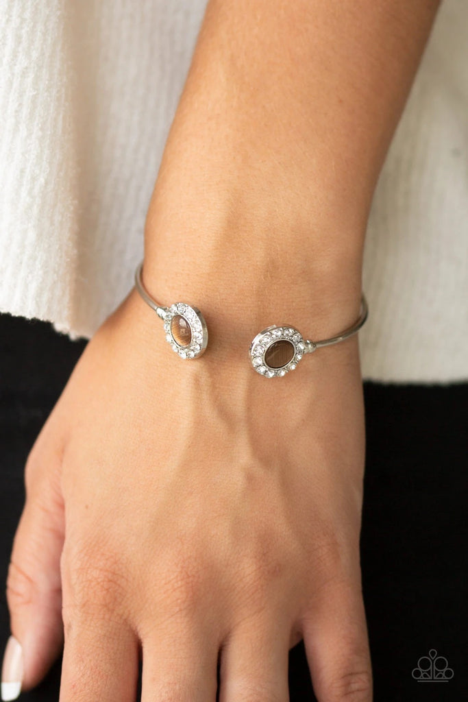 Featuring glowing brown cat's eye stones, glittery white rhinestone encrusted fittings dot the ends of a dainty silver cuff for a refined flair.  Sold as one individual bracelet.  