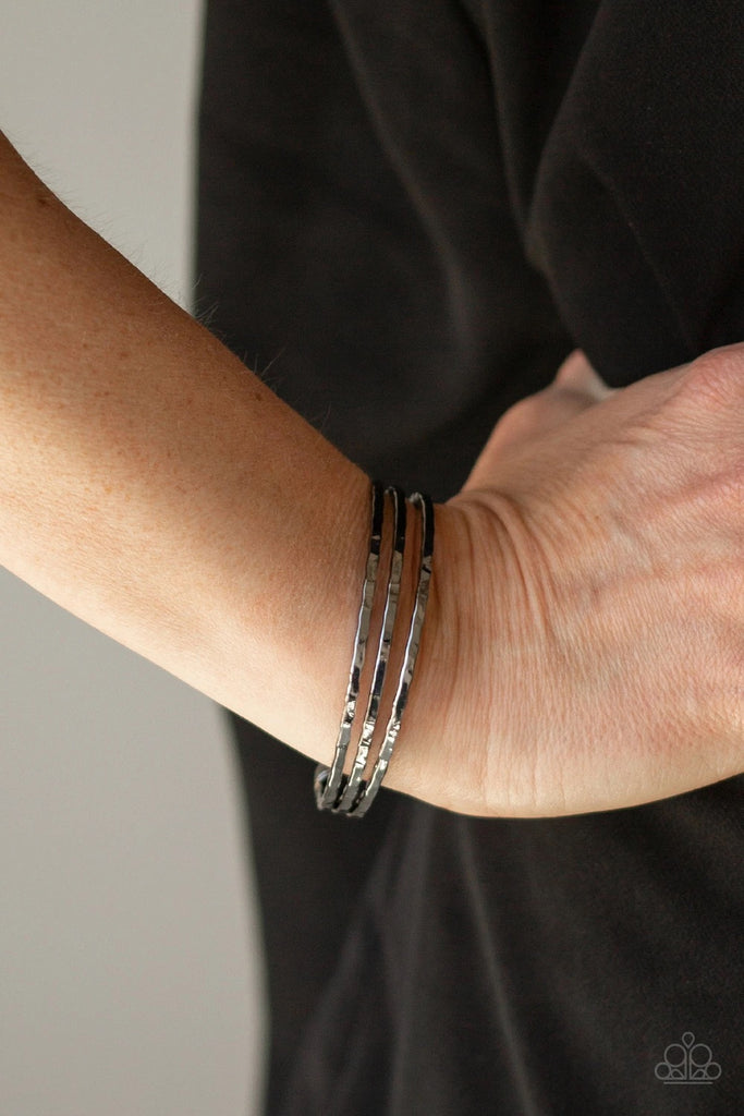 A trio of hammered gunmetal bars arc across the wrist, coalescing into a dainty cuff.  Sold as one individual.