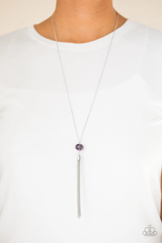 A glittery purple crystal-like bead swings from the bottom of a lengthened silver chain, giving way to a shimmering silver tassel for a glamorous finish. Features an adjustable clasp closure.  Sold as one individual necklace. Includes one pair of matching earrings.
