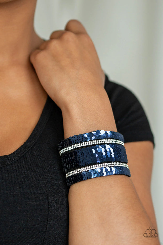 Infused with strands of blinding white rhinestones, row after row of shimmery sequins are stitched across the front of a spliced black suede band. Bracelet features reversible sequins that change from silver to blue. Features an adjustable snap closure.  Sold as one individual bracelet.