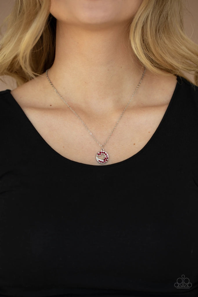 Featuring an airy heart cutout, a glittery red rhinestone encrusted silver disc swings from the bottom of a dainty silver chain below the collar for a romantic flair. Features an adjustable clasp closure.  Sold as one individual necklace. Includes one pair of matching earrings.
