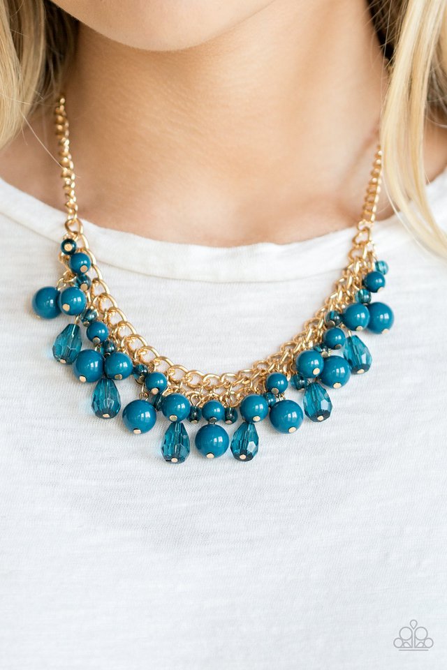 Varying in shape, glassy and polished blue beads swing from the bottom of interlocking gold chains. Crystal-like teardrops are sprinkled along the colorful beading, creating a flirtatious fringe below the collar. Features an adjustable clasp closure.  Sold as one individual necklace. Includes one pair of matching earrings.