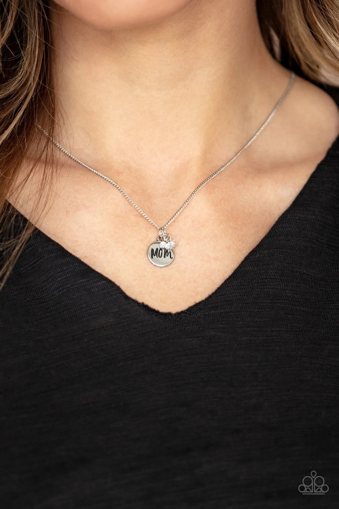 A dainty cluster of white crystal-like beads and dainty silver disc stamped in the word, "Mom", slides along a dainty silver chain, creating a sparkling pendant below the collar. Features an adjustable clasp closure.  Sold as one individual necklace. Includes one pair of matching earrings.