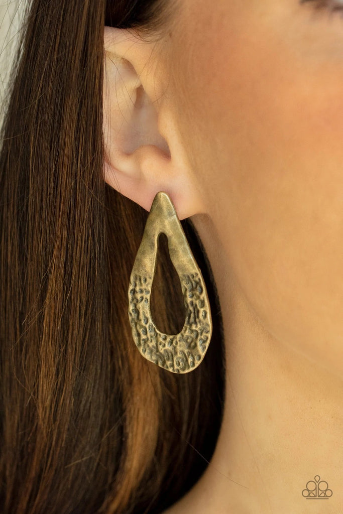 The bottom of a warped brass teardrop frame is hammered in rustic details, creating a tactile display. Earring attaches to a standard post fitting.  Sold as one pair of post earrings.