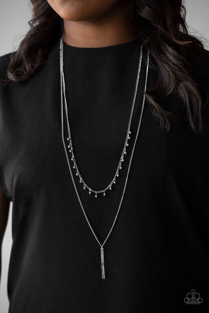 Two mismatched silver chains layer down the chest. Dainty silver beads dangle from the bottom of the uppermost chain, while a rectangular pendulum-like pendant swings from the lowermost chain for a causal finish. Features an adjustable clasp closure.  Sold as one individual necklace. Includes one pair of matching earrings.