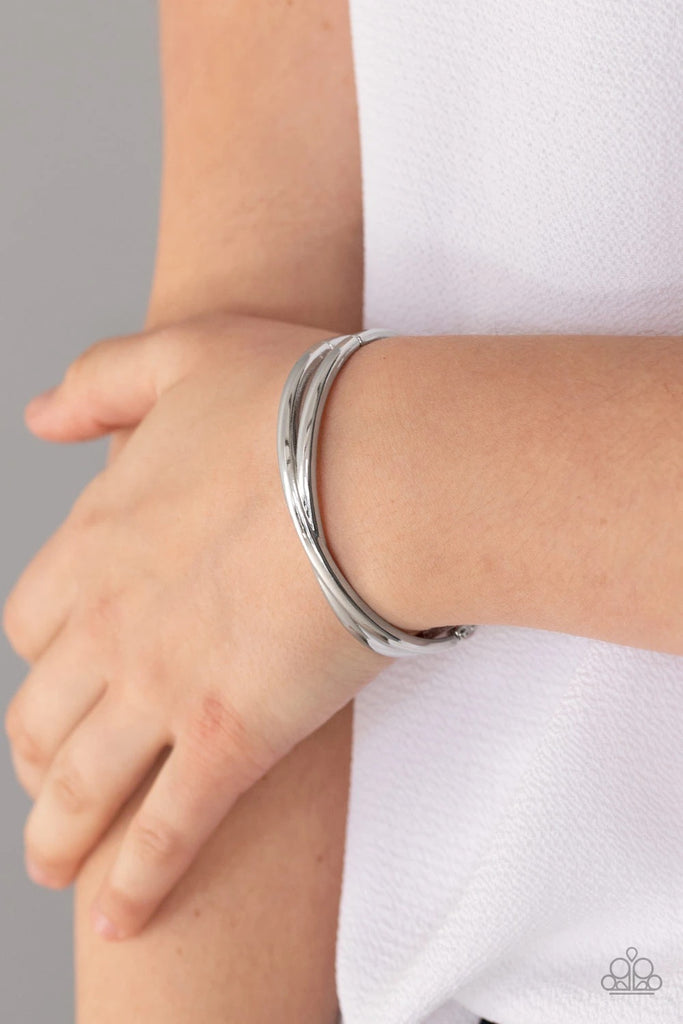 Brushed in a high sheen finish, glowing silver bars delicately crisscross across the wrist, coalescing into a dainty cuff-like bangle. Features a hinged closure.  Sold as one individual bracelet.