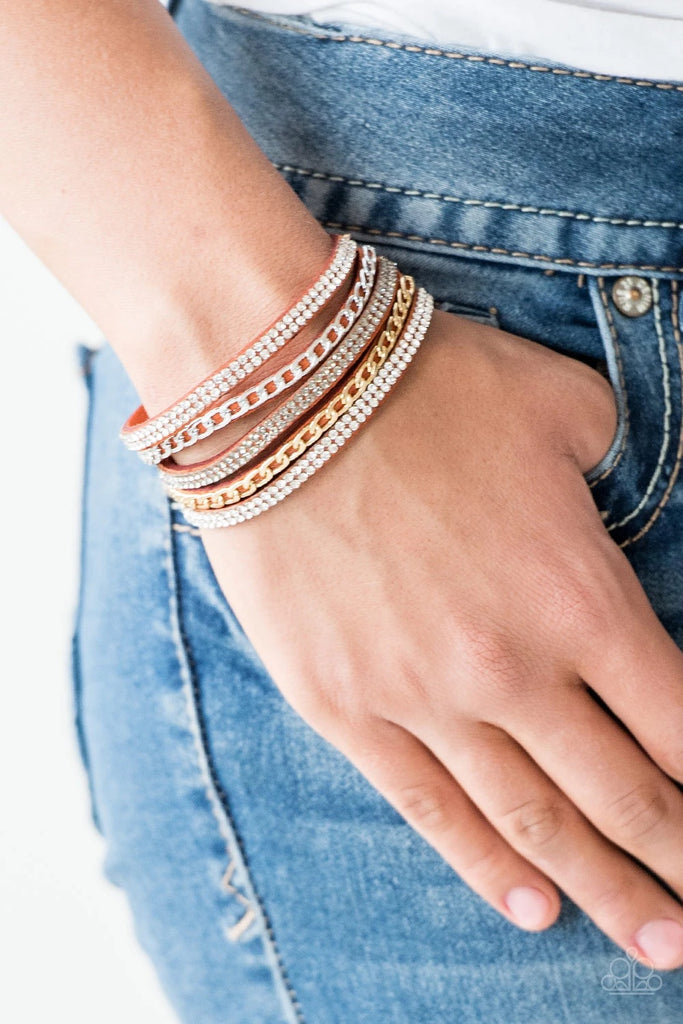 Glassy white and smoky rhinestones are encrusted along strands of orange suede. Glistening silver and gold chains are added to the bands, adding edgy industrial shimmer to the sassy palette. Features an adjustable snap closure.  Sold as one individual bracelet.