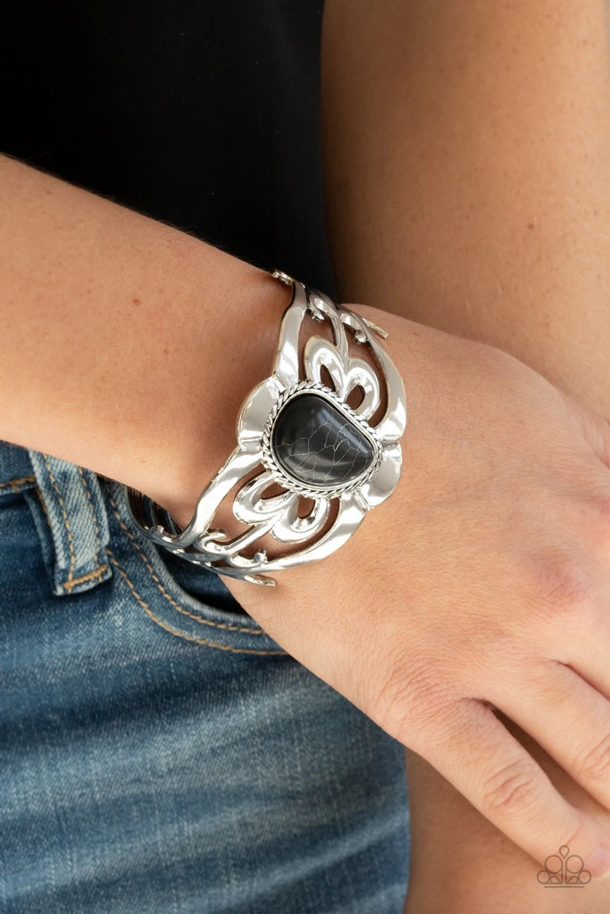 An asymmetrical black stone is pressed into the center of a silver cuff layered with filigree patterns around the wrist for a rustic flair.  Sold as one individual bracelet.