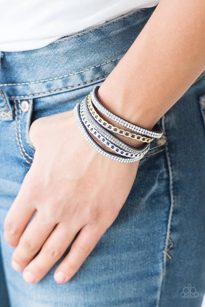 Glassy white and smoky rhinestones are encrusted along strands of blue suede. Glistening silver and gold chains are added to the bands, adding edgy industrial shimmer to the sassy palette. Features an adjustable snap closure.  Sold as one individual bracelet.  