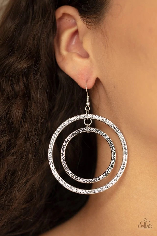 Mismatched silver hoops swing from the ear, creating a collision of metallic texture. Earring attaches to a standard fishhook fitting. Sold as one pair of earrings.