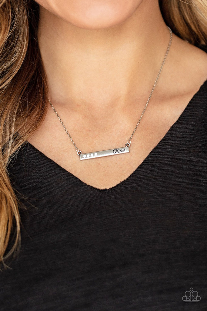 Dotted in dainty white rhinestones, a dainty silver rectangular frame stamped in the word, "Mom", is suspended by a dainty silver chain below the collar for a charming look. Features an adjustable clasp closure.  Sold as one individual necklace. Includes one pair of matching earrings.