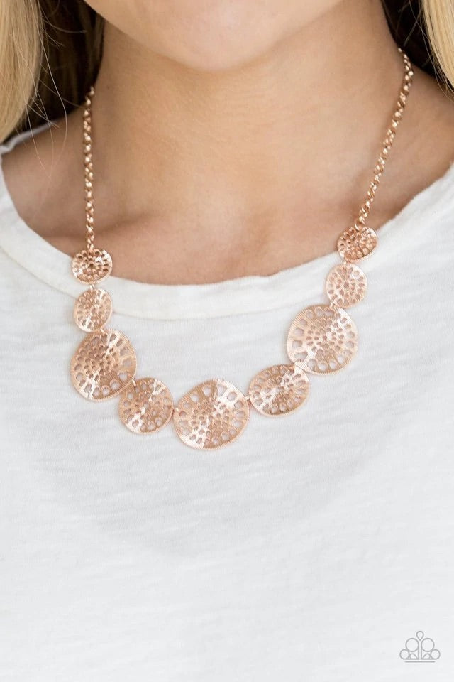Featuring airy stenciled patterns, shimmery rose gold discs link below the collar for a whimsical asymmetrical look. Features an adjustable clasp closure. Sold as one individual necklace. Includes one pair of matching earrings.