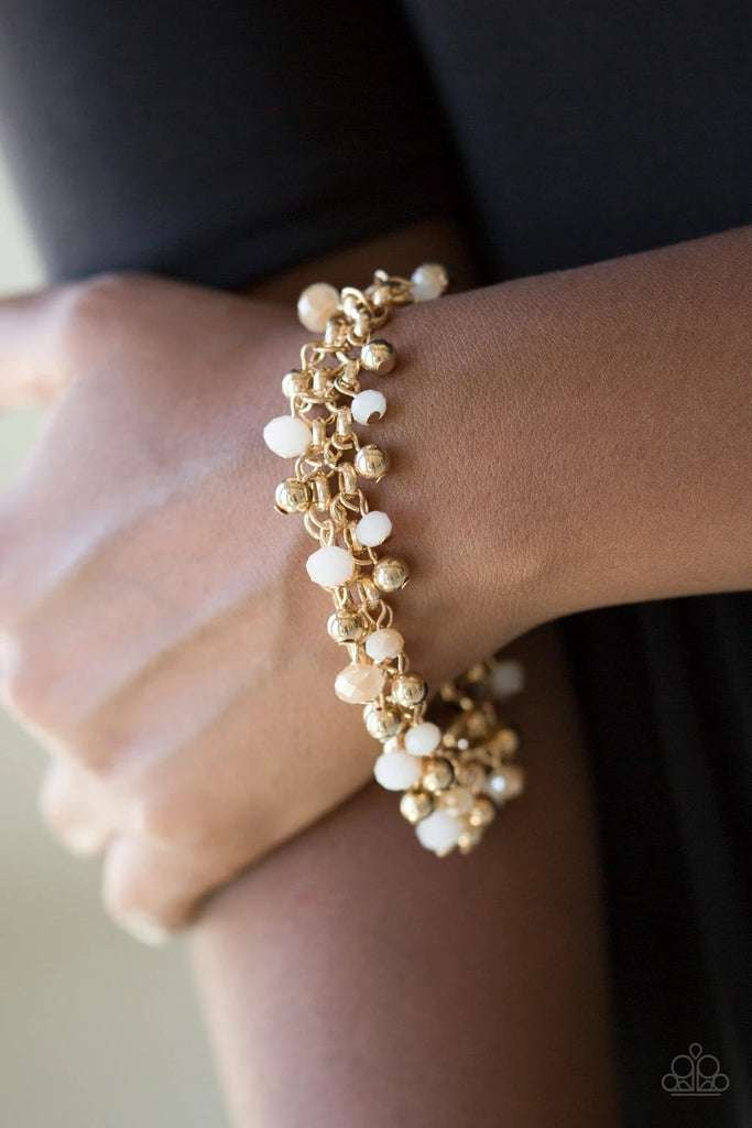 Dipped into a golden metallic shimmer, faceted white beads and classic gold beads swing from interlocking gold chains, creating a refined fringe around the wrist. Features an adjustable clasp closure.  Sold as one individual bracelet.