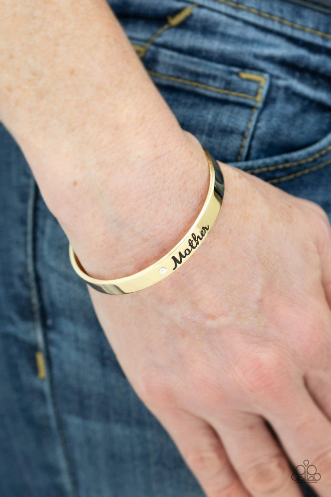 A sleek gold cuff wraps around the wrist in a casual fashion. Dotted with a dainty white rhinestone, the shimmery cuff is engraved in the word “Mother” for a loving finish.  Sold as one individual bracelet.