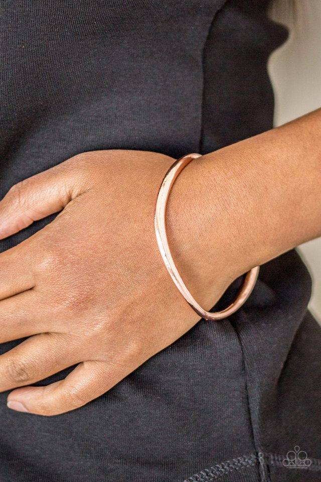 Featuring a warped surface, an asymmetrical shiny copper bangle slides along the wrist for an edgy look. Sold as one individual bracelet.